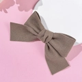 Dettaglio di un fermaglio a fiocco in velluto cachi su sfondo rosa e bianco raffinato - Kaki