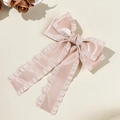 Makro-Detail der aprikosenfarbenen Satinschleife mit Rüschenrand und langen Bändern - Rosa