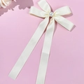 Dettaglio di un fermaglio per capelli in seta crema con perla e lunghi nastri eleganti - Beige