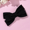 Detail view of double-layered black velvet bow hair clip on elegant pink background - Black