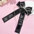 Detail einer schwarzen Satin-Haarspange mit Schleife, Bändern und cremefarbener Kordelverzierung - Schwarz