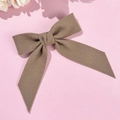 Classic dark brown wool bow hair clip with long ribbons on soft pink background - Khaki