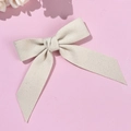 Elegant beige bow hair clip with wool texture and long ribbons on a pink background - Milky White