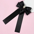 Detail of black satin ribbon bow clip with faux pearl and rhinestone center on pink background - Bow Ribbon Style / Black