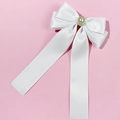 Close-up of a white satin bow hair clip featuring a pearl centerpiece and long ribbons - Bow Ribbon Style / White