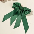 Vue détaillée du nœud en satin vert foncé avec longs rubans élégants sur fond crème épuré - Vert de Noël