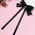 Detail einer eleganten schwarzen Satin-Haarschleife mit langen Bändern auf rosa Grund - Schwarz