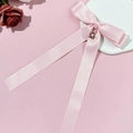 Détail de la pince à cheveux noeud en satin rose avec pendentif fleur et perle blanche - Rose