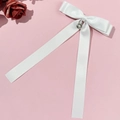 Détail d'un nœud à cheveux en satin blanc avec pendentif fleur perlé sur fond rose - Blanc