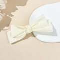 Dettaglio della clip per capelli a fiocco in velluto crema con decoro rosa su vassoio - Beige