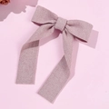 Detailed close-up of a pink knitted bow hairclip with long ribbons and soft ribbed texture - Pink