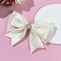 Détail de la barrette à nœud blanc crème avec bordure en dentelle et perle centrale - Beige