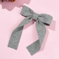 Macro shot of grey knitted ribbon bow with ribbed texture on a pink backdrop - Gray