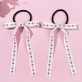 Detail of floral embroidered long bow hair ties with red hearts on a light pink background - Style 1 Red Heart Blue Floral