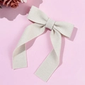 Detail of cream white knitted bow hair clip with vertical ribbed texture and long ribbons - Beige