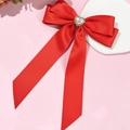 Détail d'une barrette à nœud en satin rouge avec perle de cœur et strass brillants - Rouge