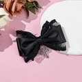 Detail of Gothic black lace bow hair clip with vintage silver cross pendant on pink background - Black
