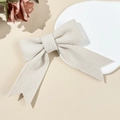 Detailed macro view of beige knitted bow hair clip with elegant soft texture - Beige
