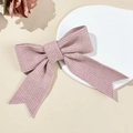 Detail of pink knitted ribbon bow hair clip showing textured vertical rib knit pattern - Pink