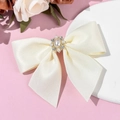 Macro dettaglio del fiocco in raso crema con grappolo floreale di strass e perle eleganti - Beige