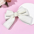 Detail of cream-white bow hair clip featuring checkered jacquard fabric and black scalloped edges - Beige