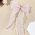 Pink organza bow hair clip with central pearl and rhinestones on a warm background - Pink