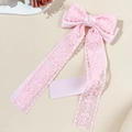Detail von rosa Spitzen-Haarschleife mit feiner Stoffstruktur und langen fließenden Bändern - Rosa