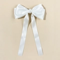 Close-up of white satin bow hair clip with elegant long ribbons on light beige backdrop - White