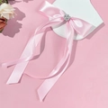 Detalle de lazo de satén rosa con centro de perlas y cintas largas fluidas elegantes - Rosa