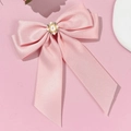 Detail of pink satin bow hair clip featuring a central pearl and rhinestone ornament - Pink