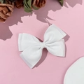Dettaglio di un fermaglio per capelli con fiocco in gros-grain bianco su sfondo rosa - Bianco