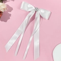 Detalle de lazo para el pelo en satén blanco con perlas y strass sobre fondo rosa - Blanco