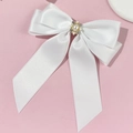 Close-up of white satin bow hair clip with vintage pearl and rhinestone center detail - White