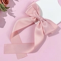 Detail of pink satin bow hair clip with long ribbons on a minimalist background - Pink