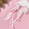 Detail of pink satin bow hair clip featuring long ribbons and elegant pearl cluster decor - Pink