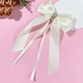 Detailed close-up of cream satin bow hair clip with pearl and rhinestone flower center - Beige