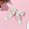 Detailed macro view of white satin bow hair clip with elegant lace trim and long ribbons - Beige