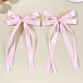 Dettaglio di fiocchi in raso rosa con perle centrali e lunghi nastri eleganti - Rosa