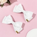 Detail von weißen Schleifen-Haarspangen mit goldenen Lucky-Anhängern auf Rosa - Weiß