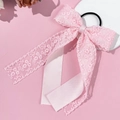 Dettaglio di un elastico per capelli in pizzo rosa con fiocco e nastri su un supporto - Rosa