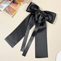 Detail of a large black satin bow hair clip with elegant long ribbons and silky texture - Black