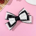 Détail d'un nœud à cheveux en dentelle blanche élégante avec bordure noire ondulée - Noir