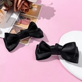 Zwei süße schwarze Satin-Haarschleifen-Clips für Damen auf elegantem rosa Hintergrund - Schwarz