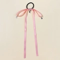 Close-up of pink satin bow hair tie with silver star and moon charms on soft background - Pink