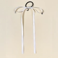 Close-up of white silk ribbon hair tie with silver moon and star charms on cream background - White