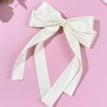 Close-up of cream white satin bow hair clip with long ribbons on pink background - Beige