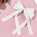 Close-up of white satin bow hair clip with long ribbons on pink background - White