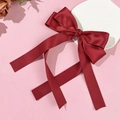 Elegant wine red satin bow hair clip with long ribbons on a pink display stand - Burgundy
