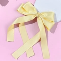Detailed view of elegant light yellow satin ribbon bow hair clip accessory for styling - Yellow