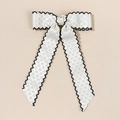 Détail d'un nœud en satin blanc avec bordure brodée ondulée noire pour accessoire cheveux - Texture Satin Blanc (Bord Festonné Noir)